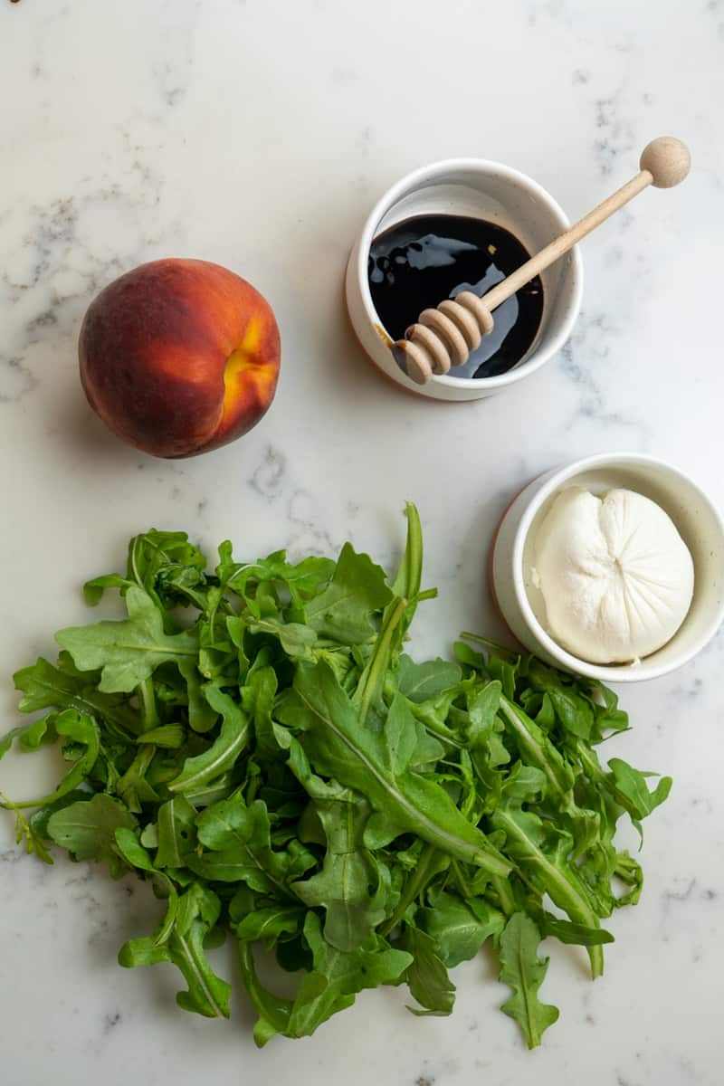 This Burrata Peach Arugula Salad is made with peaches, baby arugula, creamy burrata and topped with a balsamic glaze.