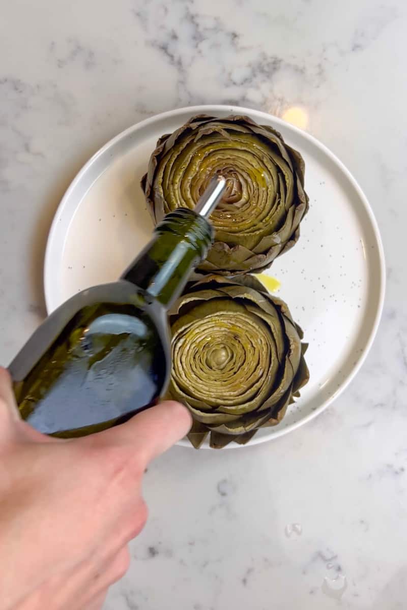 Take the artichokes out and drizzle with olive oil and season with salt.