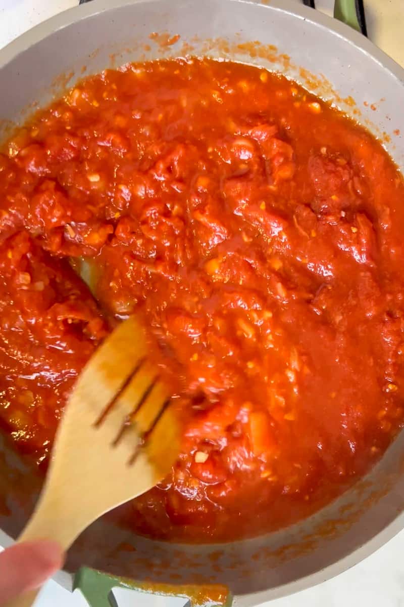 Add the hand crushed San Marzano tomatoes and a teaspoon of red pepper flakes.  Sprinkle salt and pepper and simmer sauce over medium heat for about 10-15 minutes. 