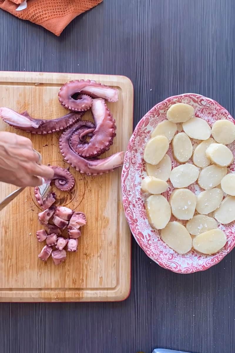 Rinse the potatoes under cold water until cool, then slice. Arrange the sliced potatoes on a serving platter, spread out. Drain the octopus and slice the tentacles into bite size pieces. 