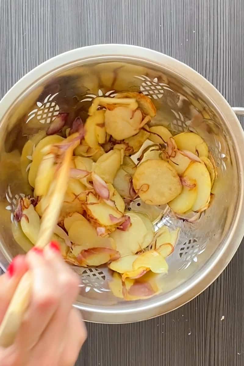 As the potatoes cook, beat eggs with some salt and pepper in a large bowl. Drain potatoes in a colander, reserving oil. Wipe out skillet and heat the skillet over a medium flame for a minute. Add two tablespoons of the reserved oil. Gently mix the potatoes in with the beaten eggs and let the potatoes soak for 15 minutes in the eggs.