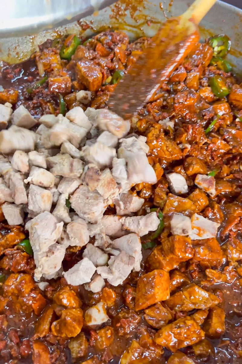 Meanwhile in a very large pan on medium high heat, brown the pork for about 10 minutes, stirring frequently. We want to just sear it. Remove and set on a plate. Toss in the chorizo, minced garlic and bacon, stirring frequently until browned, about 8 minutes. Pour in the sauce and bring to a simmer. 