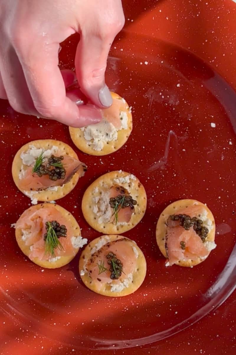 Take a slice of smoked salmon and fold or roll it into a neat shape. Place the rolled smoked salmon on top of the cream cheese layer on each cracker. If you're using caviar, spoon about ¼ teaspoon onto each smoked salmon roll.