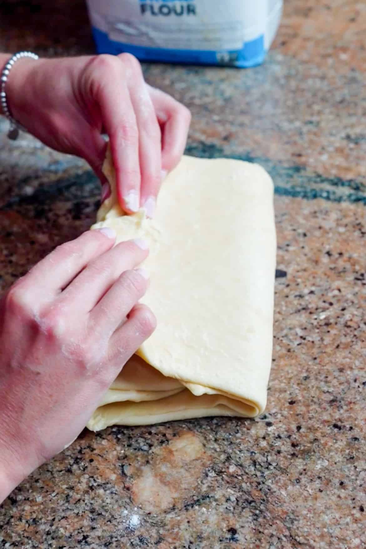 On a lightly floured work surface, use a floured rolling pin to roll out the dough to a rectangle roughly 8" x 15" in size and about ⅛" thick, with the short side facing you. Fold the dough like a business letter, bringing the bottom third of the dough up and the top third of the dough down and over the top; this is called a letter fold. This is your first turn.  Rotate the dough 90° (a quarter turn), then repeat the rolling and folding process. As you work, dust the work surface, your hands, and the rolling pin with flour as necessary to prevent sticking. If the dough starts to soften at any point, refrigerate it briefly and then continue. Wrap the dough and refrigerate it for at least 1 hour and up to 3 hours. Repeat the rolling and folding process one more time (for a total of 3 turns), then wrap the dough well and refrigerate it overnight, or at least 8 hours. 
